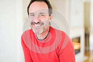 Handsome middle age man smiling looking at the camera at home