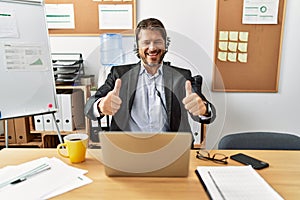 Handsome middle age man wearing call center agent headset at the office approving doing positive gesture with hand, thumbs up