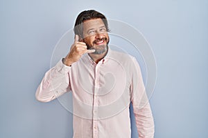 Handsome middle age man wearing elegant shirt background smiling doing phone gesture with hand and fingers like talking on the