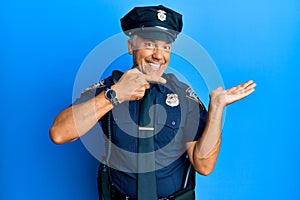 Handsome middle age mature man wearing police uniform amazed and smiling to the camera while presenting with hand and pointing