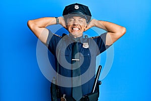 Handsome middle age mature man wearing police uniform relaxing and stretching, arms and hands behind head and neck smiling happy