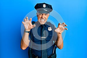 Handsome middle age mature man wearing police uniform smiling funny doing claw gesture as cat, aggressive and sexy expression