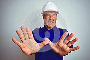 Handsome middle age worker man wearing uniform and helmet over isolated white background afraid and terrified with fear expression