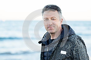 Handsome middle-aged man at the beach. Attractive happy smiling mid adult male model posing at seaside, sunset o sunrise. Outdoor