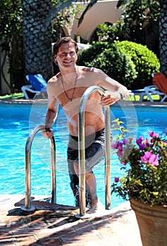 Handsome middle aged man climbing out of swimming pool