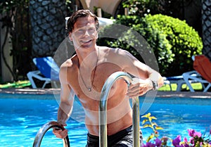 Handsome middle aged man climbing out of swimming pool