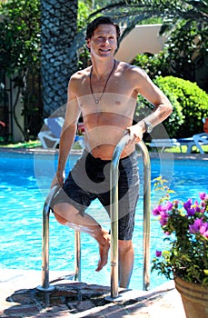 Handsome middle aged man climbing out of swimming pool