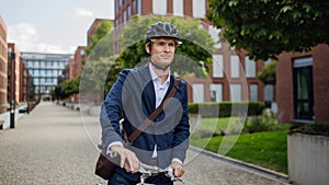 Handsome middle-aged man commuting through the city by bike in suit. Male city commuter traveling from work by bike