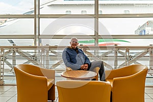 handsome middle aged man sitting in waiting room at port - Happy tourist traveling with cruise ship