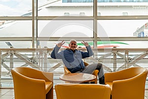 handsome middle aged man sitting in waiting room at port - Happy tourist traveling with cruise ship