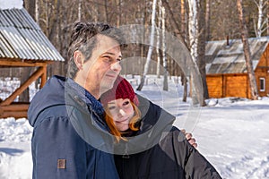 Handsome middle aged man and teen girl spending time at countryside in winter sunny day. Father and daughter walking in cottage