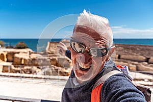 handsome middle aged man visiting tarraco archaeological complex, Tarragona - Happy tourist taking a selfie in front of roman photo