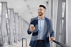 Handsome Middle Eastern Man With Smartphone In Hands Waiting In Airport Terminal