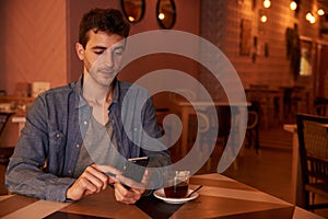 Handsome millenial in restaurant with cellphone
