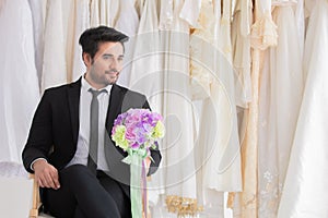 Handsome mix race beard groom hold flowers bouquet waiting for bride while fitting wedding dress,. happy smart man with tuxedo
