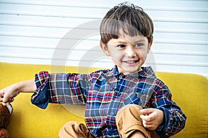 Handsome mixed race boy,  happy fun and smile with wearing a long sleeve shirt on sofa at preschool or nursery and child hospital