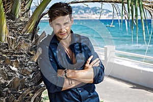 Handsome model posing under the palm tree