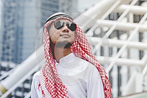 Handsome modern Arabian man standing in modern city wear muslim dress headscarf eastern ethnic smile outside office. Arab Man
