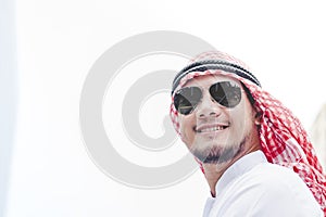 Handsome modern Arabian man standing in modern city wear muslim dress headscarf eastern ethnic smile outside office. Arab Man