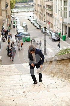 Mulatto guy walking down steps with newspaper.