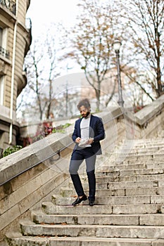 Mulatto guy walking down steps with newspaper.