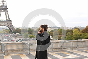 Arabian boy walking near Eiffel Tower with smartphone in slow mo