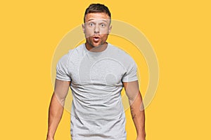 Handsome muscle man wearing casual grey tshirt scared and amazed with open mouth for surprise, disbelief face