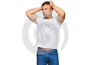 Handsome muscle man wearing casual white tshirt doing bunny ears gesture with hands palms looking cynical and skeptical