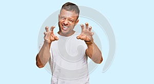 Handsome muscle man wearing casual white tshirt smiling funny doing claw gesture as cat, aggressive and sexy expression