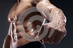 Handsome muscular bodybuilder shows his fist and vein.