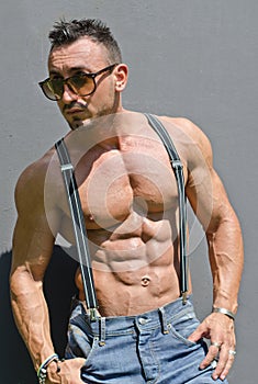 Handsome, muscular bodybuilder with suspenders shirtless