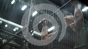 Handsome muscular built man doing chin-ups in modern fitness club.