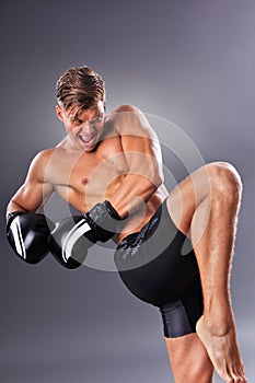 Handsome Muscular Fighter Practicing Knee Kick. Martial Arts Concept.