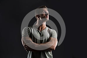 Handsome muscular fit young man on dark background looking up