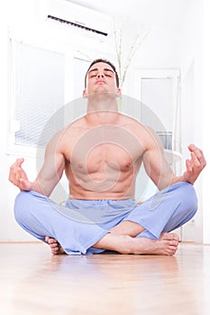 Handsome muscular half naked man doing yoga and meditating