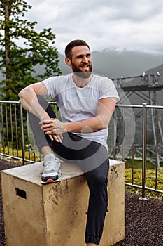 Handsome muscular hunk man looking at mountains from the peak.