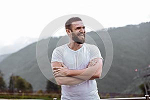 Handsome muscular hunk man looking at mountains from the peak.