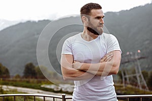 Handsome muscular hunk man looking at mountains from the peak.