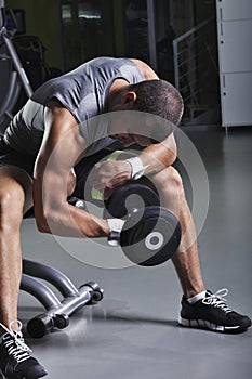 Handsome Muscular Male Model in a Sitting Position Doing Biceps