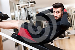 Handsome muscular man doing sit-ups on a incline bench