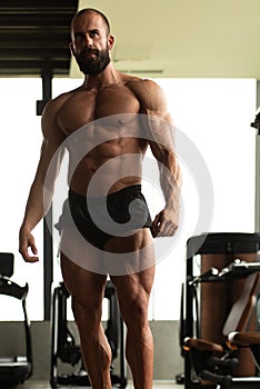 Handsome muscular man flexing muscles in gym