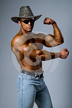 Handsome muscular man in a hat showing his muscles