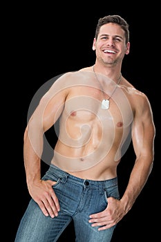 Handsome muscular man posing in blue jeans smiling at camera