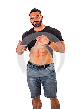 Handsome,muscular man pulling up t-shirt revealing abs. Isolated