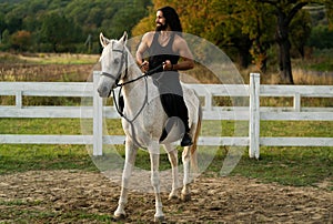 Handsome muscular man riding horse. Hunky cowboy. Young muscular guy in t-shirt on horseback. photo
