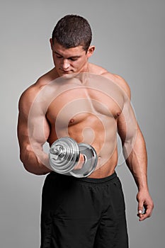 Handsome muscular man working out with dumbbells