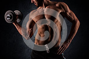 Handsome muscular man working out with dumbbells over black back