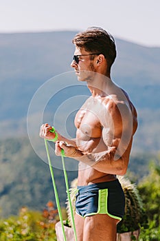 Handsome muscular man workout with Rubber Band outdoors