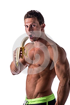 Handsome muscular shirtless man eating banana