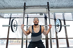 Handsome muscular weightlifter at gym doing squats